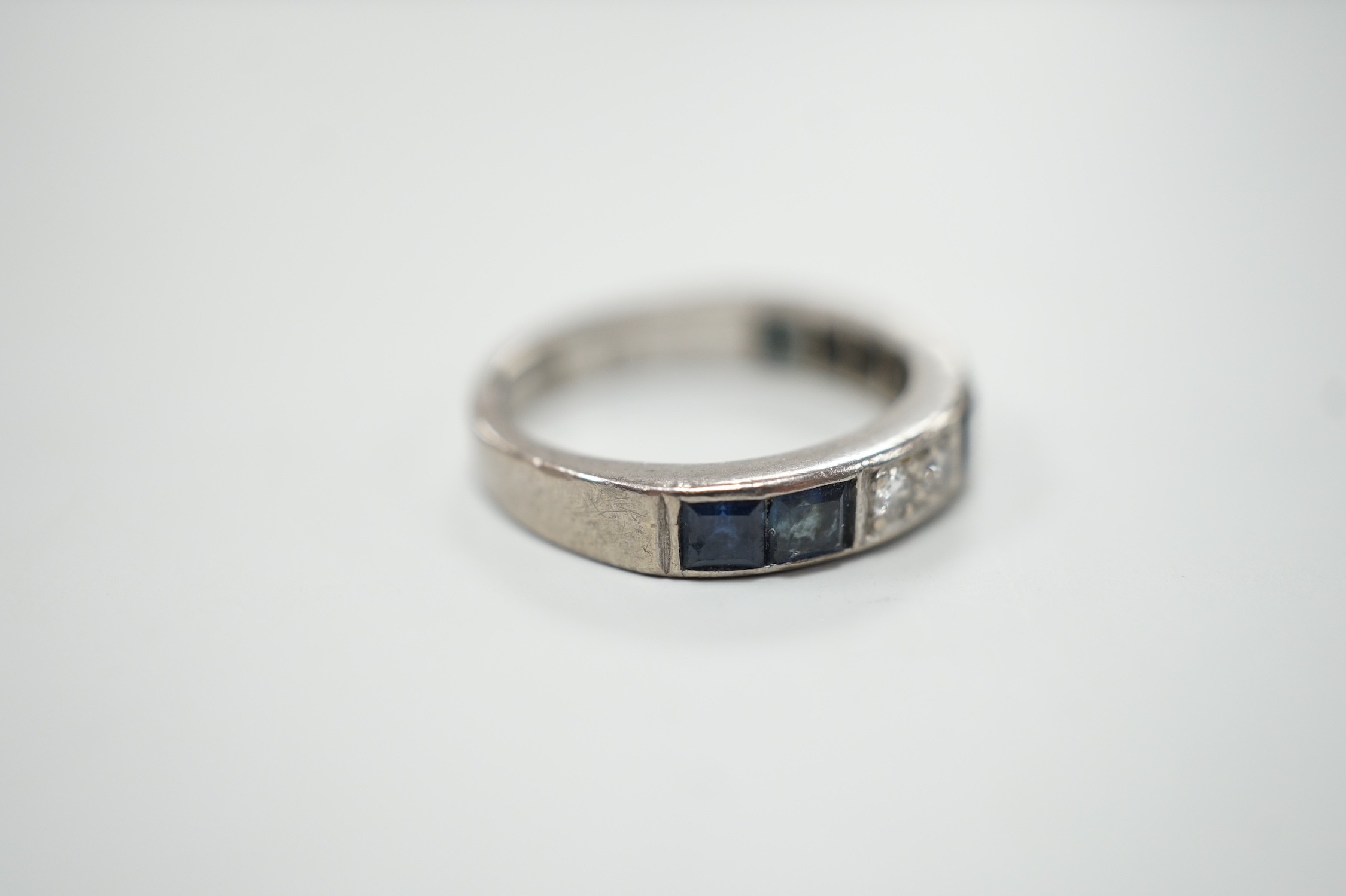 A modern 18ct white gold, six stone sapphire and four stone diamond set half eternity ring, size M, gross weight 5.2 grams.